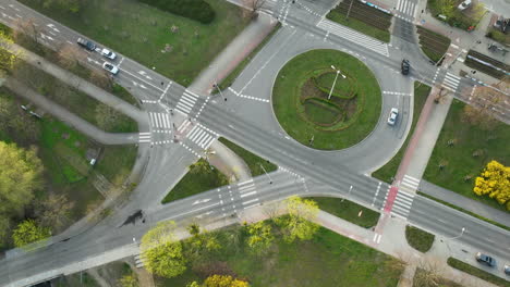 Aerial-view-of-a-roundabout-with-its-orderly-traffic-flow-and-crosswalks,-set-amid-the-green-spaces-of-a-cityscape