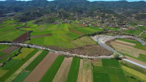 River-Flows-Through-Green-Parcels-in-a-Village-Landscape:-Cultivated-Land-Thriving-in-Spring,-Nestled-in-a-Beautiful-Valley-in-Albania