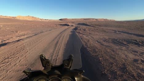 POV:-Moto-rider-drives-over-ruts-on-bumpy-gravel-desert-road-in-Chile