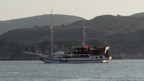 Kleines-Touristenboot-Kreuzt-Den-Ozean-Vor-Der-Kulisse-Eines-Berges-Auf-Der-Insel-Komodo