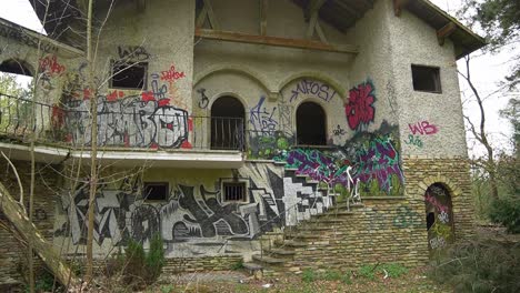 Abandoned-mansion-exterior-view-of-entrance,-walls-painted-with-graffiti