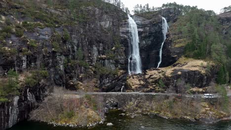 Group-of-tourists-admire-Hesjedalsfossen-waterfall-in-Norway-at-springtime