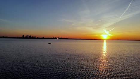 Antena-Establecida-De-La-Capital-De-Tallin,-Estonia-Al-Atardecer,-Olas-Actuales-Del-Mar-Báltico-Y-Horizonte-Urbano-A-Distancia-De-La-Capital-Europea