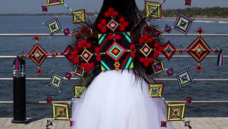 Woman-from-back-in-white-tulle-dress-with-colorful-Eyes-of-God-from-Wixarika-culture