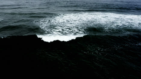 Small-waves-roll-across-dark-surface-of-Pacific-Ocean,-static-aerial-view