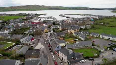 dramatic-drone-push-past-church-in-Dingle-Ireland-and-flies-down-to-boats-in-harbor-on-overcast-day-on-peninsula