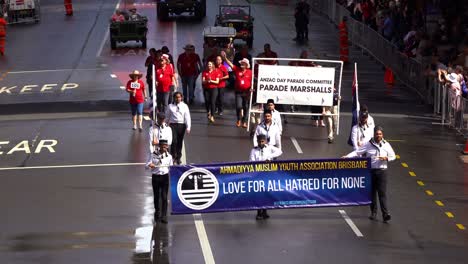 Representatives-from-the-Ahmadiyya-Muslim-Youth-Association-holding-the-banner-with-slogan-of-love-for-all-hatred-for-none,-walking-down-the-street,-participating-in-Anzac-Day-parade-in-Brisbane-city