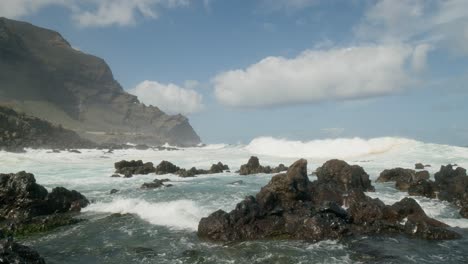 Slowmotion-ocean-waves-crushing-on-sharp-volcanic-rocky-beach-near-Punta-Negra,-Buenavista-del-Norte,-Tenerife,-Canary-Islands-in-spring
