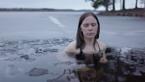 An-ice-bathing-woman-puts-her-hands-together-and-calmly-breathes,-slider-shot