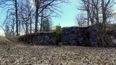 Remains-of-medieval-castle-stone-wall,-dolly-out-on-sunny-spring-day