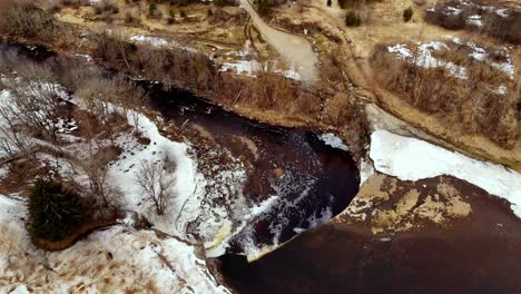 Aerial-approaching-view-of-partly-frozen-Jegala-Waterfall,-Estonia