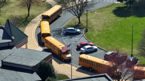 American-school-scene-of-traditional-yellow-school-buses-parking-on-entrance-of-school-in-spring