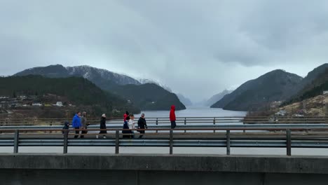 Grupo-De-Turistas-Caminando-Sobre-Un-Puente-Con-Impresionantes-Vistas-Hacia-Veafjord