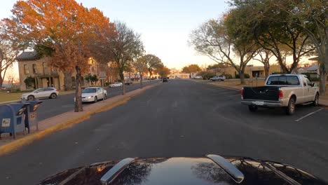 Car-driving-past-Gillespie-County-courthouse,-Fredericksburg,-Texas,-USA,-POV-wide-shot