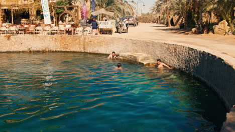 Local-kids-swimming-inside-a-salt-pool-in-Siwa-oasis,-Qattara-Depression-and-the-Great-Sand-Sea-Desert