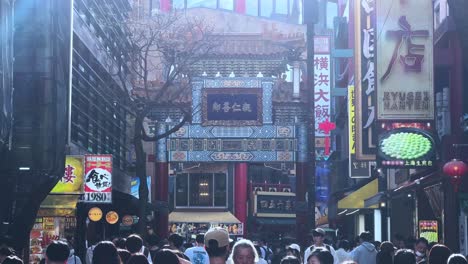 Bustling-Japanese-people-walk-urban-market-with-shops-colorful-signs-sell-spot,-spring-at-Yokohama-commercial-downtown