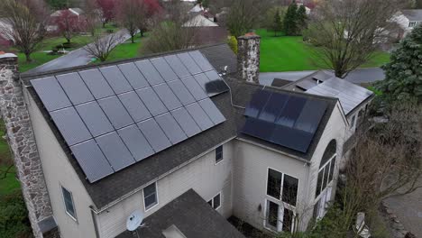 Toma-Aérea-Acercándose-A-Una-Casa-Antigua-Con-Modernos-Paneles-Solares-En-El-Techo.