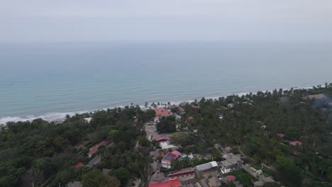 Drone-ascends-above-forested-tropical-jungle-and-oceanic-coastline-in-Palomino-Colombia