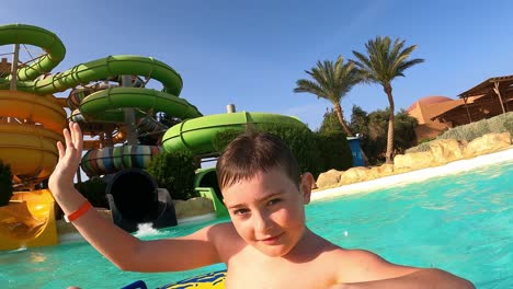 Niñito-En-Flotador-Inflable-Saliendo-Del-Tobogán-A-La-Piscina-En-Marsa-Alam,-Egipto