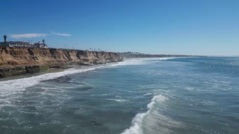 Disparo-De-Drones-Sobre-La-Soleada-Costa-Del-Océano-Con-Hermosas-Olas-Azules-Y-Un-Panorama-De-Acantilados-Costeros