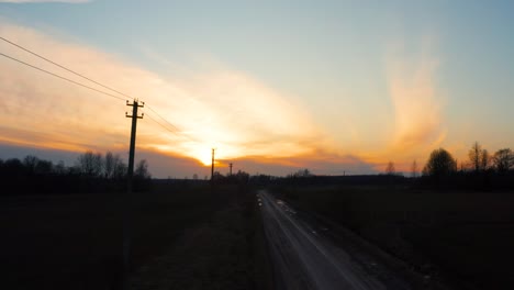 Electric-power-line-poles-and-gravel-road-during-moody-golden-hour-sunset