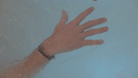 Nahaufnahme-Der-Hände-Eines-Mannes,-Der-In-Einem-Whirlpool-Entspannt,-Seine-Finger-Sind-Gespreizt-Und-An-Seinen-Handgelenken-Liegen-Armbänder