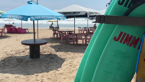 Surfboards-and-beach-umbrellas-with-empty-tables-and-chairs-on-Legian-beach,-Bali,-Indonesia