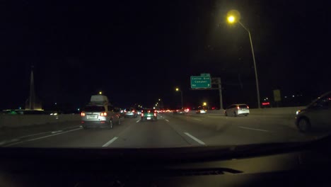 Series-number-nine-hyperlapse-showing-car-driving-away-from-downtown-Dallas-Texas-at-night-with-city-lights,-stop-and-go-traffic,-general-interstate-driving,-and-emergency-vehicle-with-lights