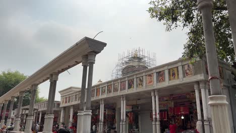 Wide-angle-view-of-scaffolding-in-kali-ghat-temple-for-construction-in-Kolkata-with-golden-shikhara-at-the-top,-India