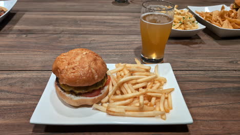 Deliciosa-Hamburguesa-Fresca-Y-Papas-Fritas-Con-Vaso-De-Cerveza-Sobre-Una-Mesa-De-Madera,-Vista-Hacia-Adelante