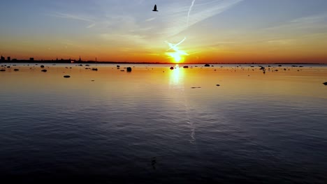 Tallinn,-Estland,-Malerischer-Sonnenuntergang-über-Der-Ostsee-Mit-Steinfelsen-Im-Wasser-Und-Der-Skyline-Der-Hauptstadt-In-Der-Ferne,-Luftaufnahmen