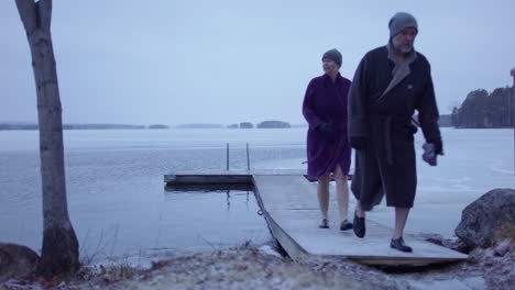 An-ice-bathing-couple-walk-back-to-land-after-bathing,-Sweden