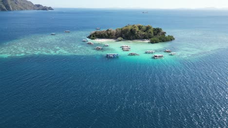 Drone-Long-Shot-of-CYC-Island-in-Coron-with-Tour-Boats-at-Reef-on-Sunny-Day