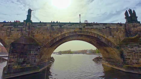 Charles-Bridge-over-the-Vltava-river-in-Prague,-Czech-Republic---floating-under-on-a-boat