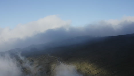 Camino-Sinuoso-Sobre-El-Volcán-Haleakala-A-La-Luz-Del-Día,-Mientras-Las-Nubes-Se-Mueven-Sobre-La-Ladera-De-La-Montaña-En-Maui,-Hawaii