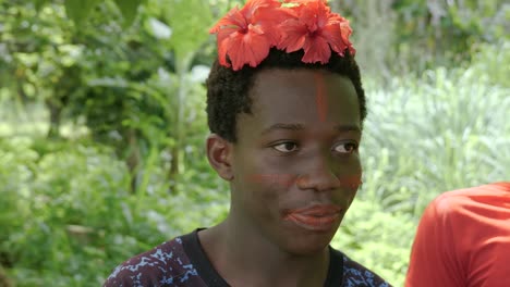 Young-black-male-wearing-Annatto-flowers-painting-Achiote-seed-pigment-onto-hair-in-tribal-rainforest-ceremony