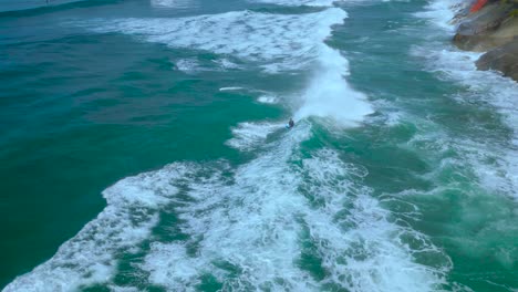 Drone-shot-of-surfers-playing-and-surfing-backwards-during-high-tide-in-Carlsbad-California