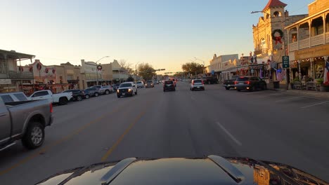 Car-driving-at-sunset-through-Fredericksburg,-Texas,-USA,-POV-wide-shot