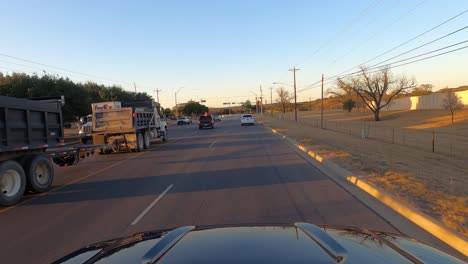 Car-driving-at-sunset-through-Fredericksburg,-Texas,-USA,-POV-wide-shot