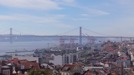 Hafenkräne-Entlang-Des-Tejo-Unter-Der-Hängebrücke-In-Lissabon,-Portugal,-An-Einem-Dunstigen,-Blauen-Morgenhimmel