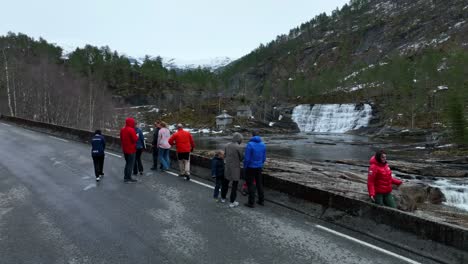 Group-of-tourists-looking-at-Waterfall-in-Eksingedalen-valley-at-spring,-Norway