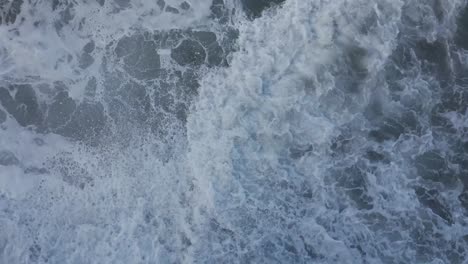 Drone-shot-straight-down-of-ocean-waves-washing-around-during-high-tide