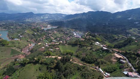 Vista-Aérea,-Paisaje-Pintoresco-De-La-Región-De-Guatape-En-Colombia,-Colinas-Verdes,-Caminos-Del-Pueblo-Y-Lago