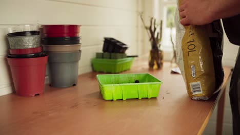 Mann-Schüttet-Gartenerde-Auf-Plastiktopf