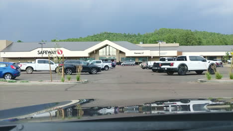 Vehicle-front-POV-of-people-moving-and-driving-near-shopping-mall,-timelapse