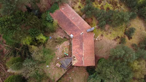 Top-down-aerial-view,-abandoned-mansion-inside-forest-with-damaged-roof