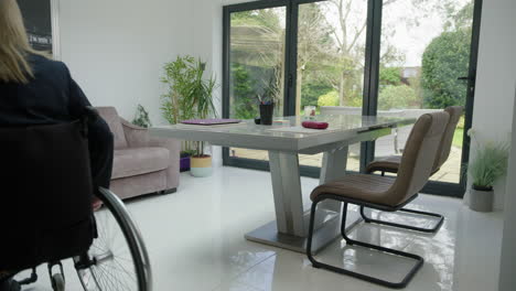 Woman-in-wheelchair-entering-home-office-wide-shot