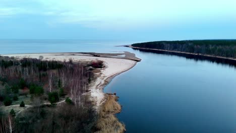 Aerial-drone-panoramic-landscape-of-river-waters-entering-Ocean-white-sand-forest-trees-wide-Landscape,-skyline-background,-natural-environment