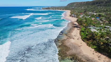 Drone-Footage-Flying-Over-North-Shore-Oahu,-Aerial-Shot-of-Sandy-Shore,-White-Waves-at-Iconic-Surf-Spot-by-Hale'iwa-Town