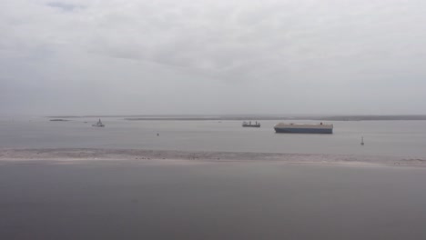 Wide-aerial-panning-shot-of-cargo-ships-on-Charleston-Harbor-during-a-hazy-day-with-low-visibility-in-Charleston,-South-Carolina